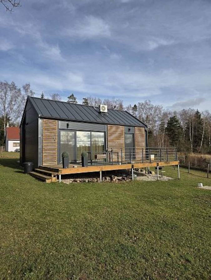 Chata Raťák s tmavou fasádou a modřínovými lamelami na trávníku